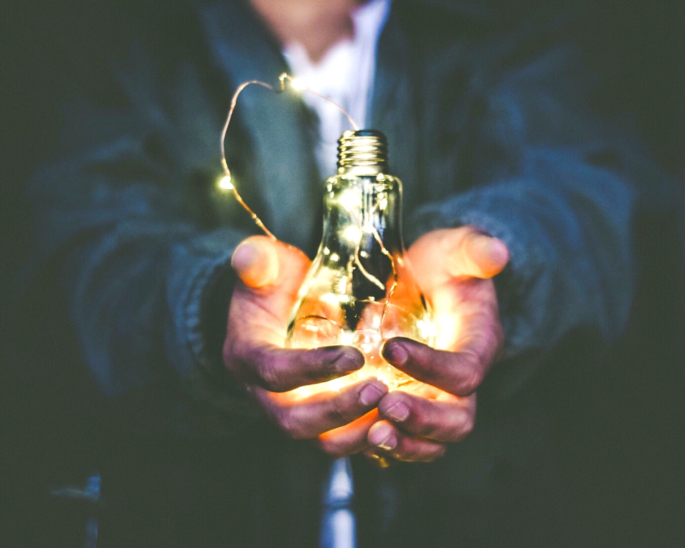 A hand holding a bulb with lights