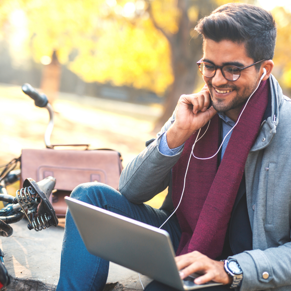 A man working on a laptop, smiling and talking