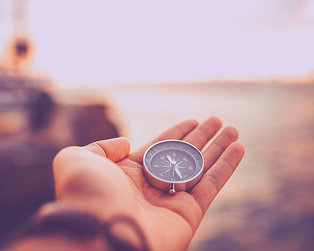 A hand holding a compass in his hand