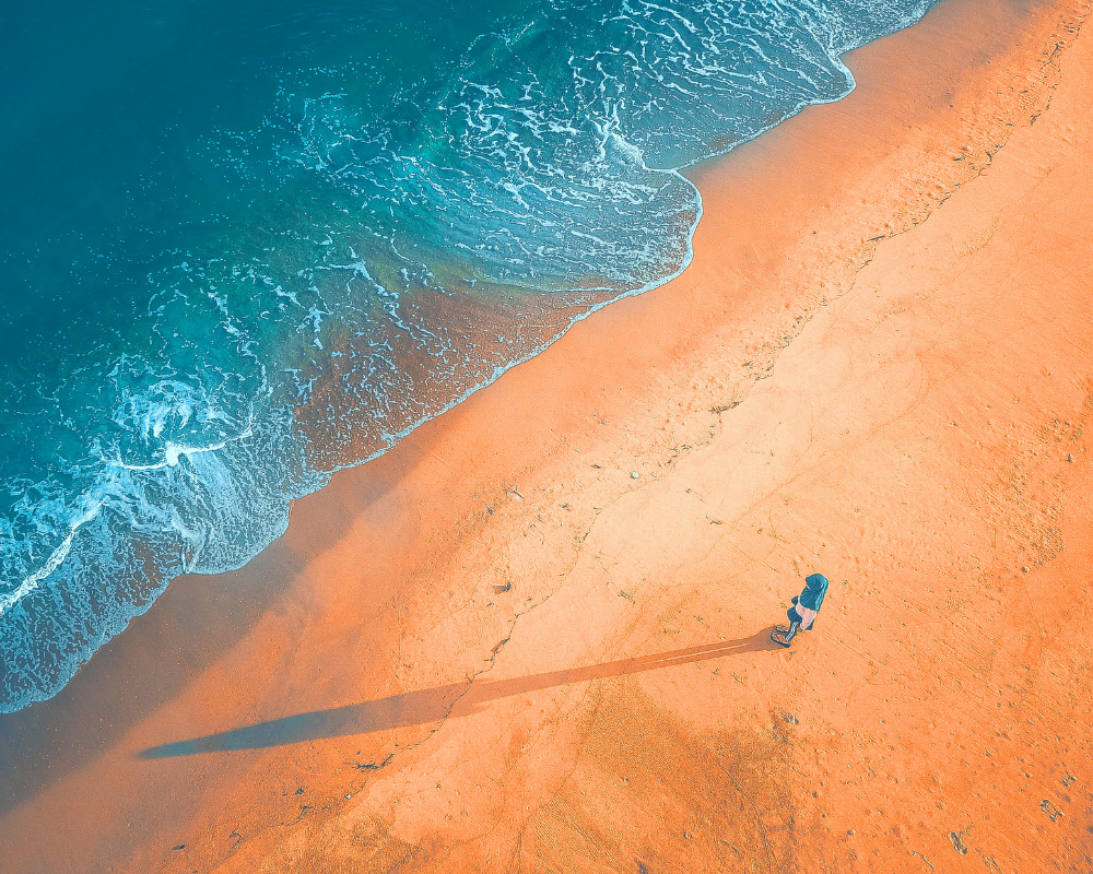 A person standing near the bank of the ocean